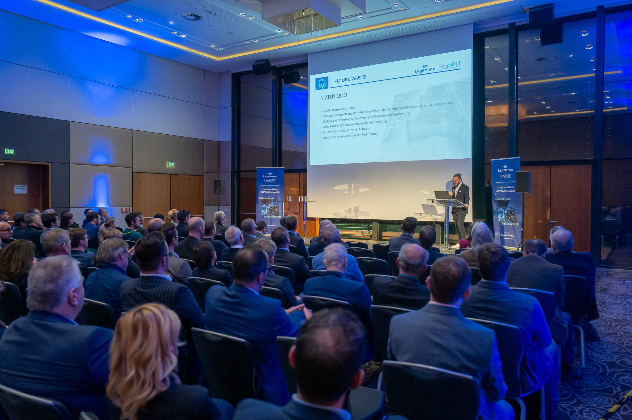 Eine Gruppe von Menschen bei einer geschäftlichen Präsentation; formelle Kleidung; gedämpftes Licht.