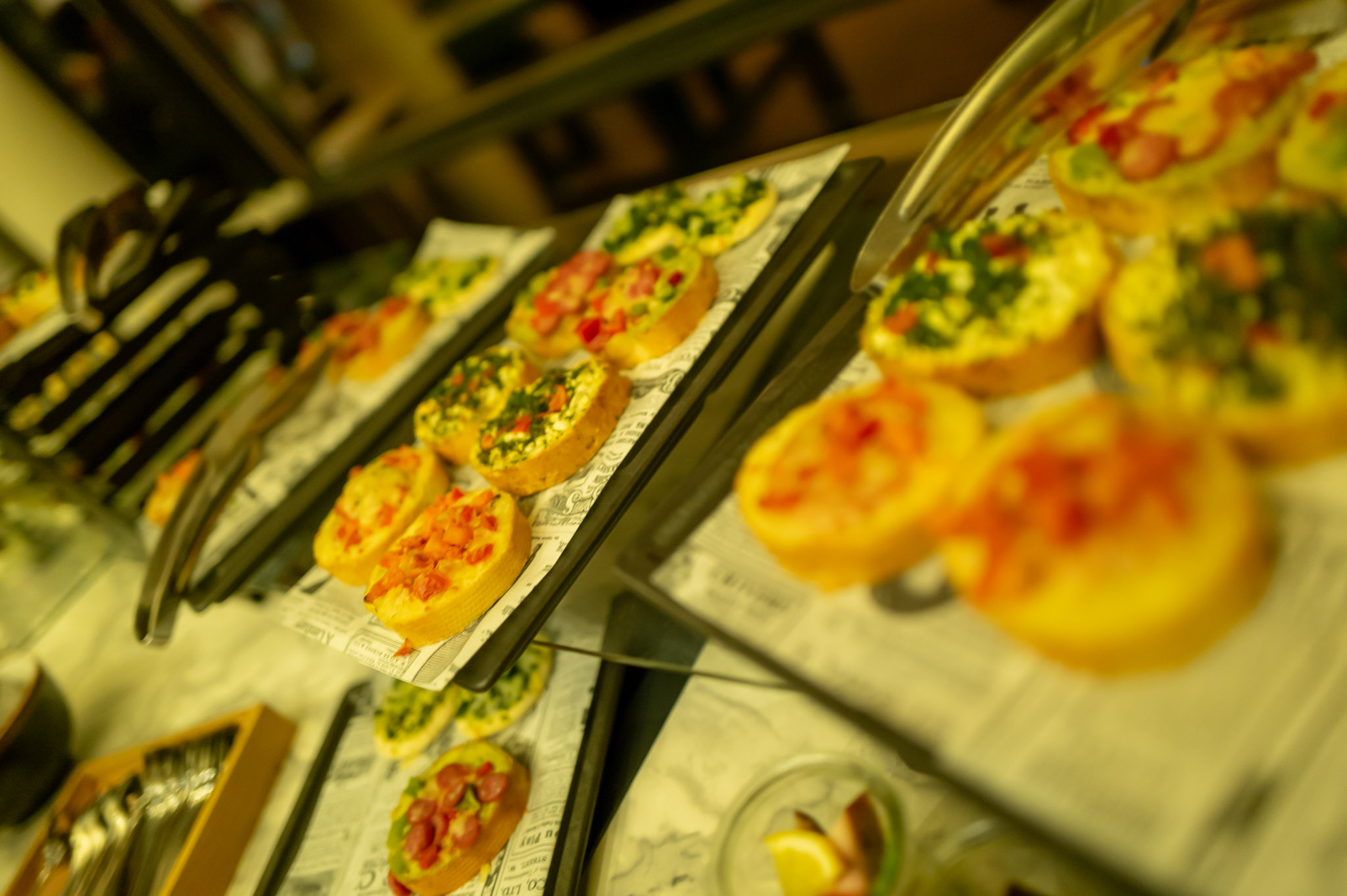 Mehrere bunte Mini-Quiches auf Tabletts mit dekorativen Zutaten angerichtet.