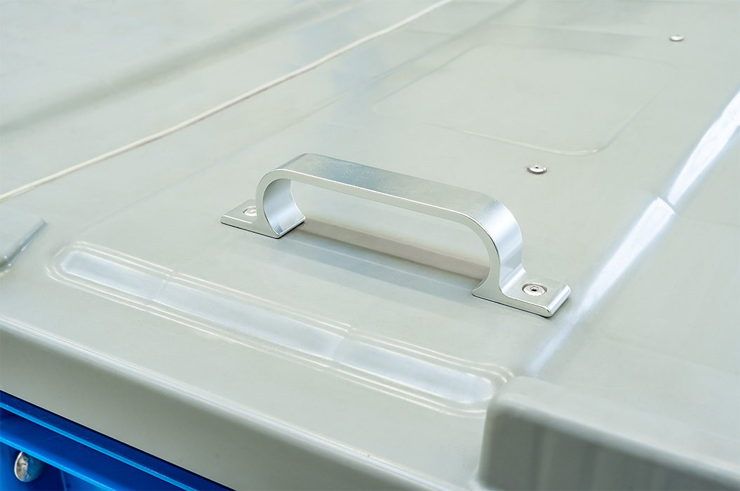A grey metal handle on a blue-grey container lid.