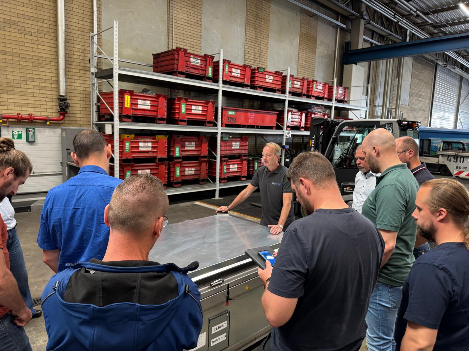 Mehrere Personen versammeln sich konzentriert um einen Tisch in einer Halle.