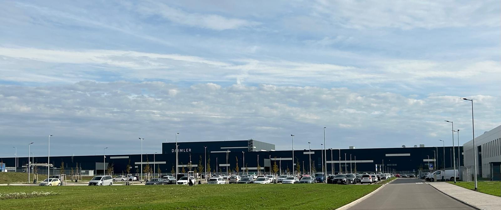 Eine grosse Daimler Industriehalle mit dunkler Fassade und vielen parkenden Autos
